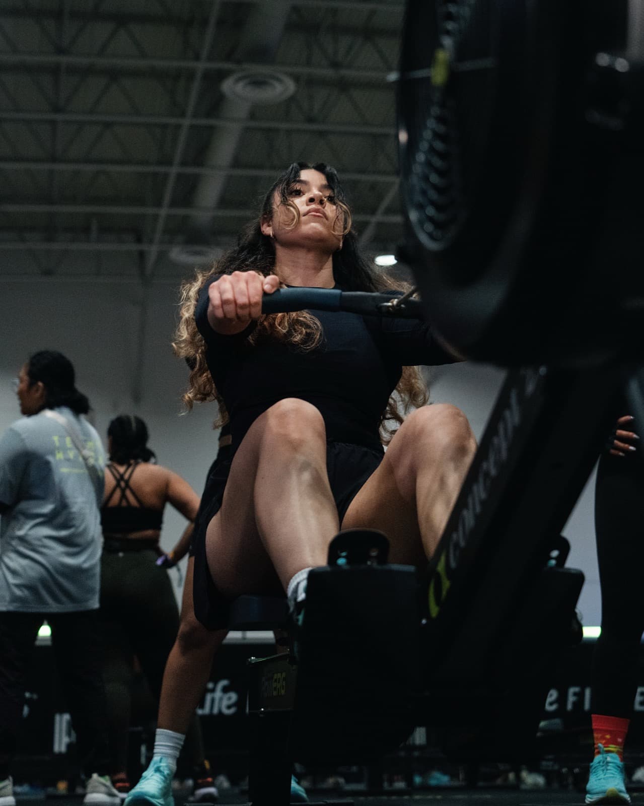 A HYROX athlete pulling on a rowing machine, shot from low down