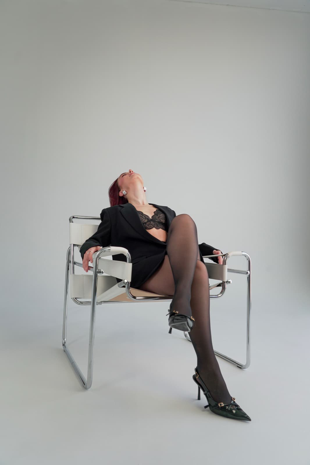Leaning back in a chrome Wassily chair, head tilted up