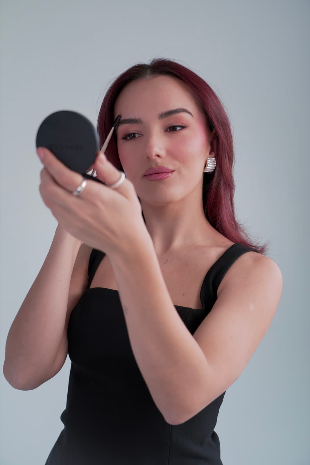 Close-up of brow grooming in a compact mirror