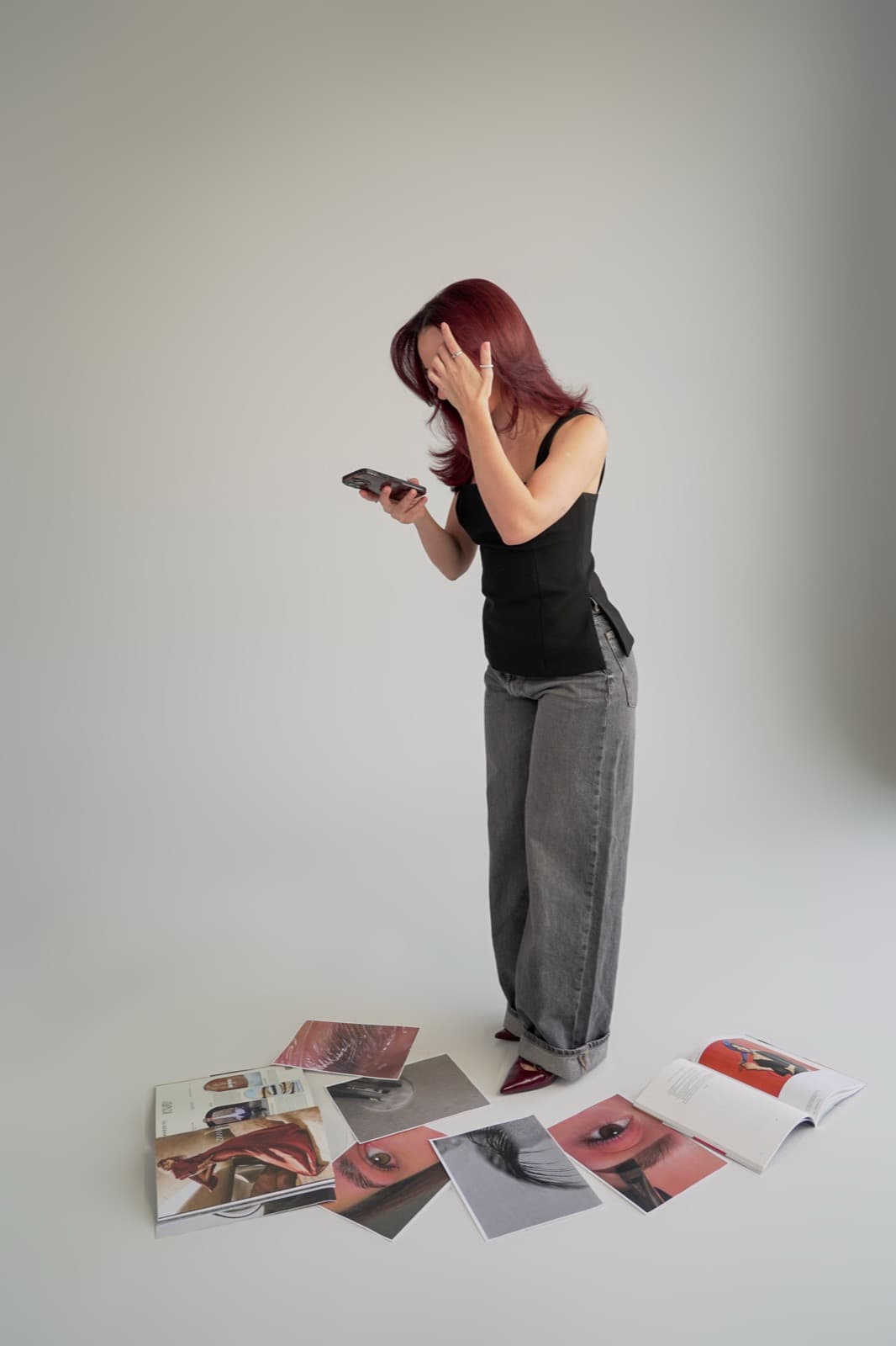 Standing over the moodboard, hand in her hair, checking her phone