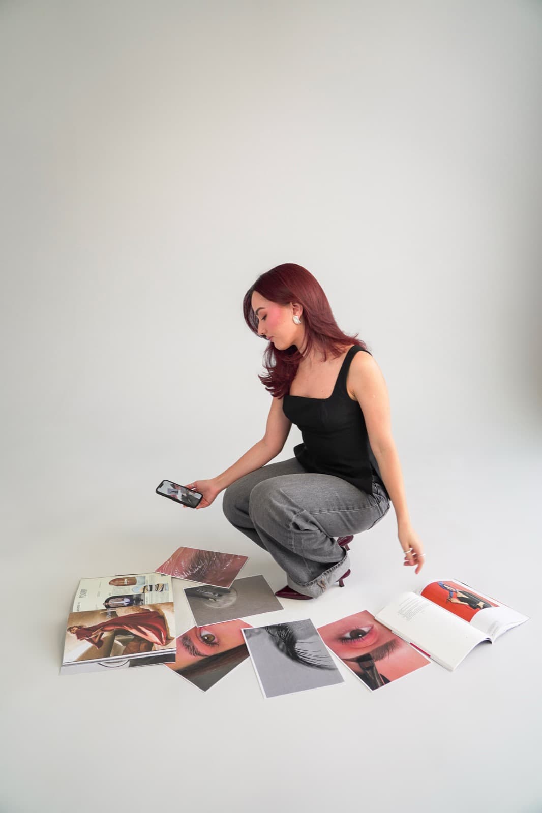 Crouched beside the moodboard, photographing the prints on her phone
