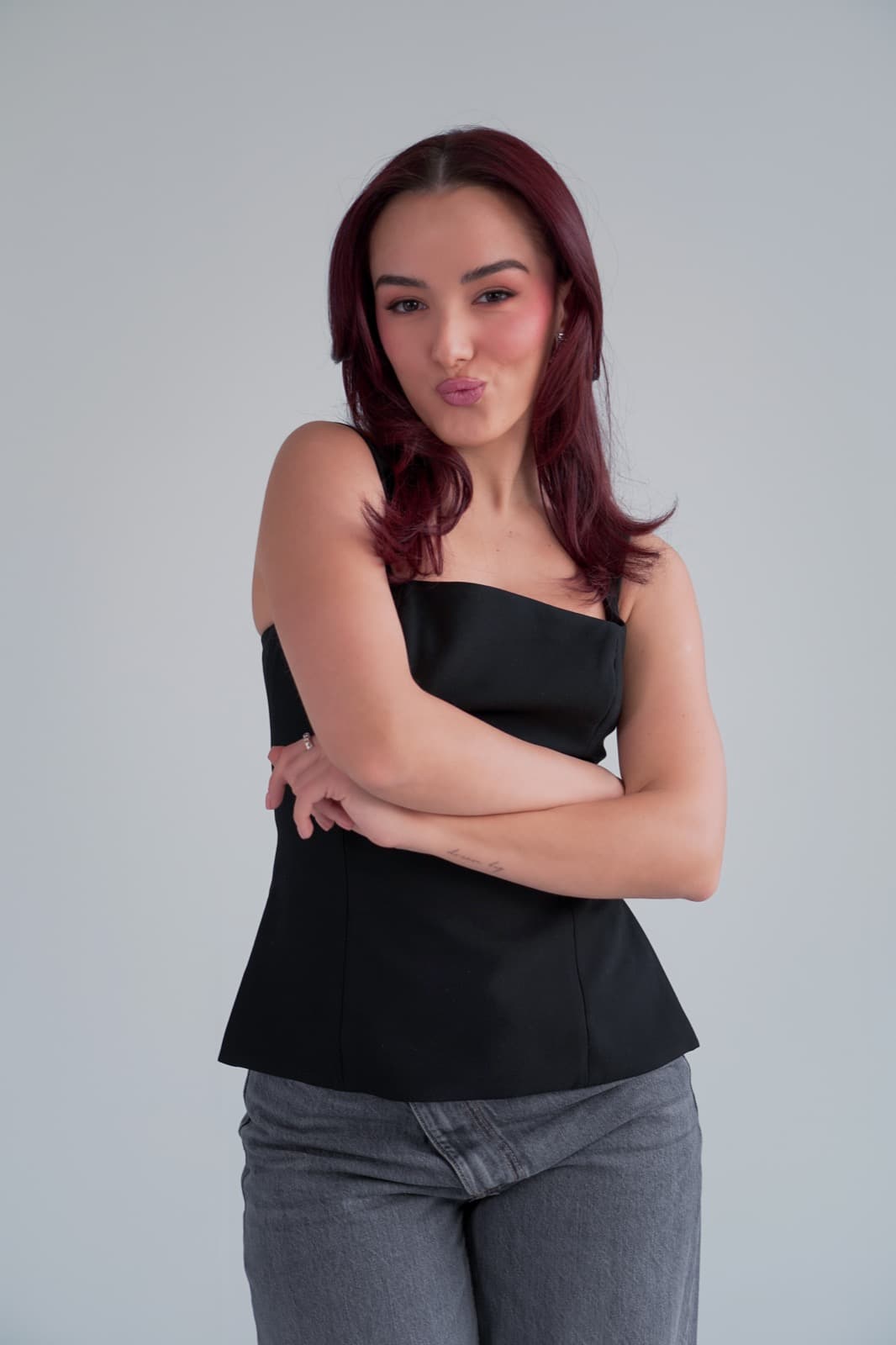 Arms folded, blowing a kiss to camera
