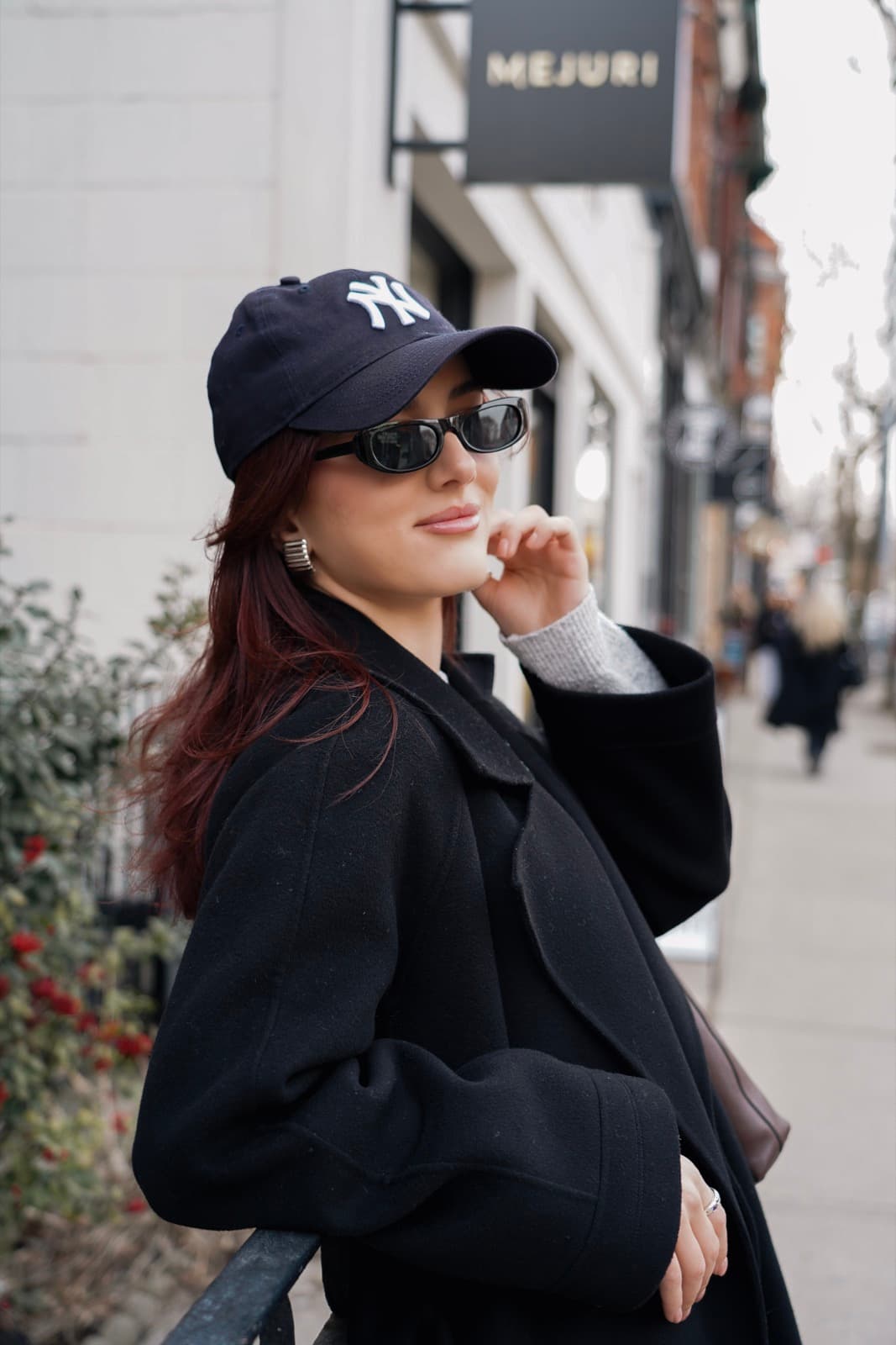 Street portrait on Ossington in a Yankees cap and sunglasses beside the Mejuri sign